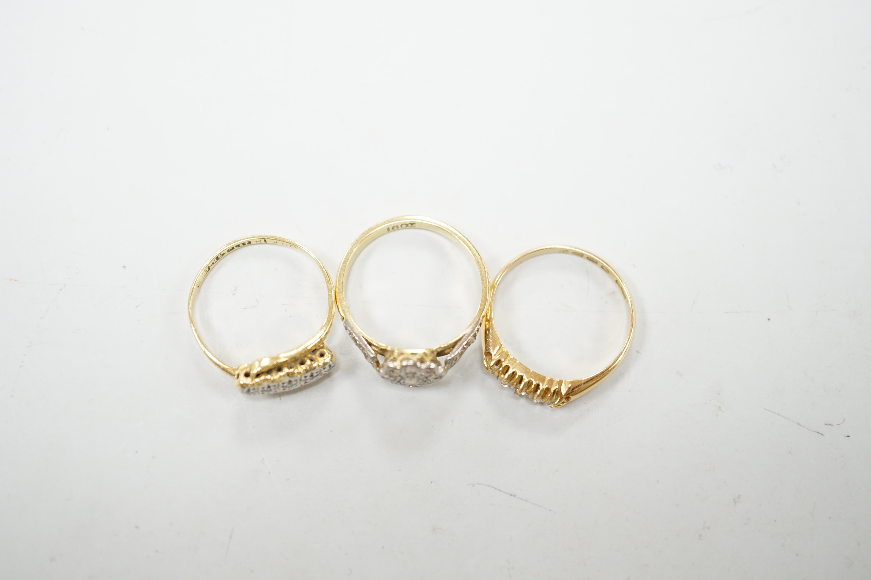 Three assorted 18ct and diamond cluster set rings including a late Victorian five stone diamond chip half hoop, gross weight 7.9 grams.